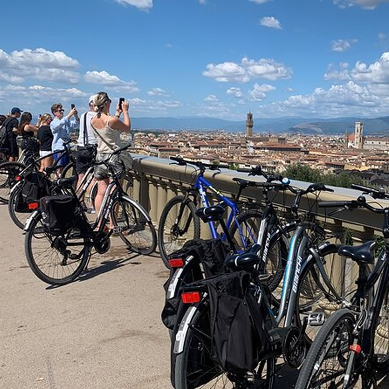 Young people on bikes taking photos of Florence's panorama